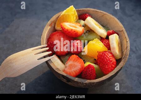 Obstsalat in einer natürlichen Schüssel aus einer halben Kokosnussschale auf einem Metalltablett Stockfoto