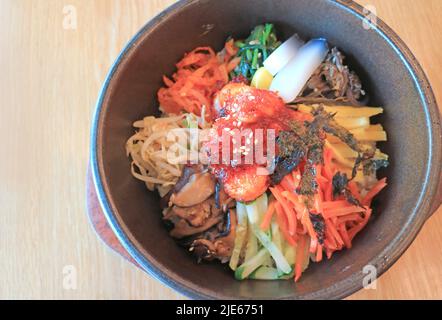 Bibimbap, ein würzig-würzig-traditioneller koreanischer gemischter Reis mit Fleisch und gemischtem Gemüse in einer Schüssel mit heißem Stein Stockfoto