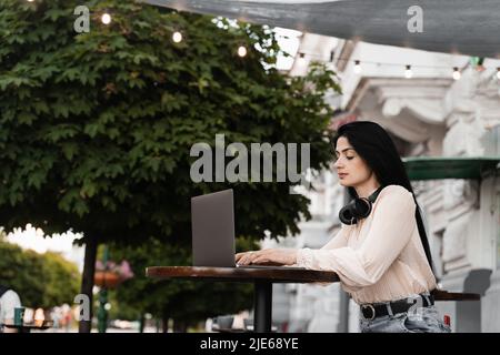 Frau mit Vitiligo Hautpigmentierung an den Händen arbeiten auf Laptop online im Freien im Café. Saisonale Hauterkrankung Stockfoto