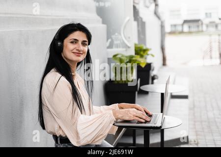 Glückliche Frau mit Vitiligo Hautpigmentierung an den Händen arbeiten auf Laptop und Musik hören. Lebensstil mit saisonalen Hauterkrankungen Stockfoto