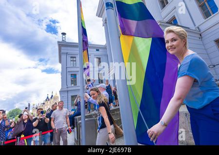 Schwerin, Deutschland. 25.. Juni 2022. Die Ministerpräsidentin von Mecklenburg-Vorpommern, Manuela Schwesig (SPD), hebt zum ersten Mal die Regenbogenfahne vor der Staatskanzlei und feiert mit den Teilnehmern am Christopher Street Day 16. unter dem Motto „Wissen schafft Vielfalt“. Farbenfroh kostümiert versammelt sich die meist jüngere Menge im Alten Garten. Die CSD soll die Menschen an die Rechte von Lesben, Schwulen, Bisexuellen, Transgender, Intersex und queeren Menschen erinnern. Quelle: Jens Büttner/dpa/Alamy Live News Stockfoto
