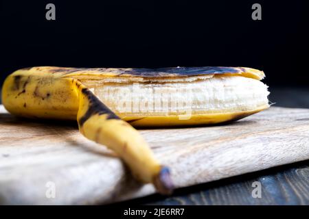 Alte, schwärzende Banane auf einem Schneidebrett, verderbliche Bananen-Fruchtnahrung Stockfoto