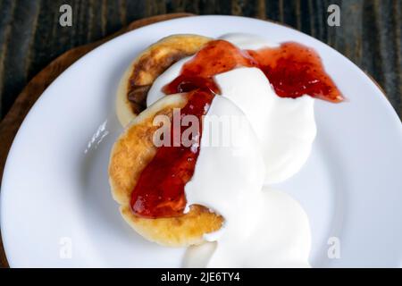 Quark-Käsekuchen werden mit Sauerrahm oder Marmelade gegessen, köstlicher Käsekuchen, der zu Hause gebacken wird Stockfoto