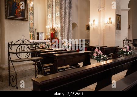 Eine Holzbänke in einem katholischen Kircheninneren Stockfoto