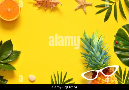 Sommerhintergrund. Palmblatt, Ananas in Sonnenbrille, Seesterne und Muschel auf gelbem Hintergrund Stockfoto
