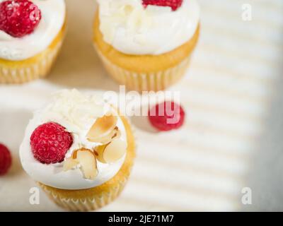 Ein leichtes Sommerdessert - leckere Muffins mit Creme, Himbeeren und Mandeln. Isoliert auf weißem Hintergrund. Nahaufnahme. Low-Angle-Ansicht. Urlaub, Stockfoto