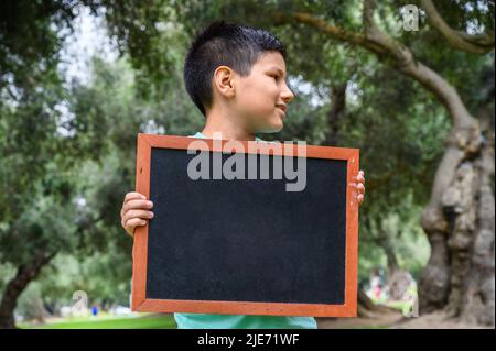 Fröhlicher lateinischer Junge mit einem Lächeln und einer Tafel Stockfoto