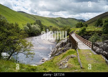 Eine Fußgängerbrücke in Glen Tilt, über den Fluss Tilt, in der Nähe von Blair Atholl, Perthshire, Schottland. Stockfoto