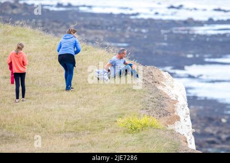 Beachy Head, Eastbourne, Großbritannien. 25.. Juni 2022. Touristen und Besucher dieser beliebten Südküsten-Klippe, die über 500 Meter am höchsten Punkt liegt, sind sich nicht bewusst, welche großen Risiken sie bei der Pose für Fotos eingehen. Die jüngsten Berichte über weitere Risse in der fragilen Kreide und regelmäßige Felsstürze stellen weiterhin ein großes Problem dar. Kredit: Newspics UK South/Alamy Live Nachrichten Stockfoto