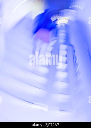 Unterführung mit einem Fußweg, bei dem Menschen den Hintergrund verwischen. Langer, leuchtender unterirdischer Tunnel und Menschen im Hintergrund. Stockfoto