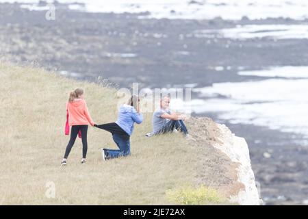 Beachy Head, Eastbourne, Großbritannien. 25.. Juni 2022. Touristen und Besucher dieser beliebten Südküsten-Klippe, die über 500 Meter am höchsten Punkt liegt, sind sich nicht bewusst, welche großen Risiken sie bei der Pose für Fotos eingehen. Die jüngsten Berichte über weitere Risse in der fragilen Kreide und regelmäßige Felsstürze stellen weiterhin ein großes Problem dar. Kredit: Newspics UK South/Alamy Live Nachrichten Stockfoto