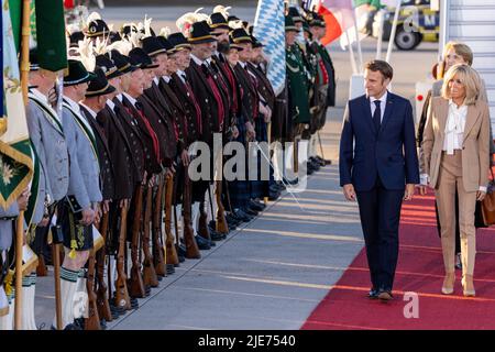 Elmau, Deutschland. 25.. Juni 2022. Frankreichs Präsident Emmanuel Macron und seine Frau Brigitte laufen am Flughafen München an bayerischen Berggeflemen und traditionellen Kostümen vorbei. Deutschland ist Gastgeber des Gipfels der wirtschaftlich starken Demokratien G7. Am ersten Tag des Gipfels werden die globale Wirtschaftslage, der Klimaschutz sowie die Außen- und Sicherheitspolitik mit den Sanktionen gegen Russland diskutiert. Quelle: Daniel Karmann/dpa/Alamy Live News Stockfoto