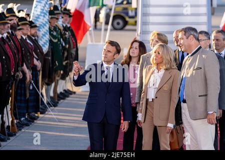 Elmau, Deutschland. 25.. Juni 2022. Frankreichs Staatspräsident Emmanuel Macron (l.) und seine Frau Brigitte laufen am Münchner Flughafen vorbei an bayerischen Berggeflemen und Trachten, nachdem sie mit dem bayerischen Ministerpräsidenten Markus Söder (r., CSU) am Flughafen München angekommen sind. Deutschland ist Gastgeber des Gipfels der wirtschaftlich starken Demokratien G7. Am ersten Tag des Gipfels werden die globale Wirtschaftslage, der Klimaschutz sowie die Außen- und Sicherheitspolitik mit den Sanktionen gegen Russland diskutiert. Quelle: Daniel Karmann/dpa/Alamy Live News Stockfoto