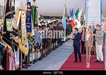 Elmau, Deutschland. 25.. Juni 2022. Frankreichs Staatspräsident Emmanuel Macron (l.) und seine Frau Brigitte laufen am Münchner Flughafen vorbei an bayerischen Berggeflemen und Trachten, nachdem sie mit dem bayerischen Ministerpräsidenten Markus Söder (r., CSU) am Flughafen München angekommen sind. Deutschland ist Gastgeber des Gipfels der wirtschaftlich starken Demokratien G7. Am ersten Tag des Gipfels werden die globale Wirtschaftslage, der Klimaschutz sowie die Außen- und Sicherheitspolitik mit den Sanktionen gegen Russland diskutiert. Quelle: Daniel Karmann/dpa/Alamy Live News Stockfoto