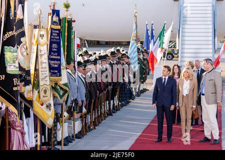 Elmau, Deutschland. 25.. Juni 2022. Frankreichs Staatspräsident Emmanuel Macron (l.) und seine Frau Brigitte laufen am Münchner Flughafen vorbei an bayerischen Berggeflemen und Trachten, nachdem sie mit dem bayerischen Ministerpräsidenten Markus Söder (r., CSU) am Flughafen München angekommen sind. Deutschland ist Gastgeber des Gipfels der wirtschaftlich starken Demokratien G7. Am ersten Tag des Gipfels werden die globale Wirtschaftslage, der Klimaschutz sowie die Außen- und Sicherheitspolitik mit den Sanktionen gegen Russland diskutiert. Quelle: Daniel Karmann/dpa/Alamy Live News Stockfoto