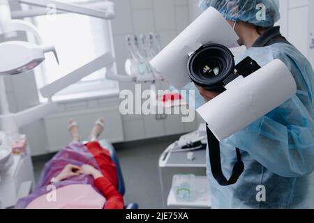 Eine Zahnärztin bereitet sich darauf vor, die Zähne des Patienten vor dem Zahnaufhellungsverfahren zu fotografieren. Seitenansicht. Hochwertige Fotos Stockfoto