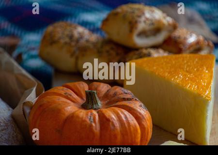 Traditionelles Herbstliches Picknick mit Sauerteig, Kürbissen und Käse auf einer rustikalen Picknick-/Platzmatte. Stockfoto