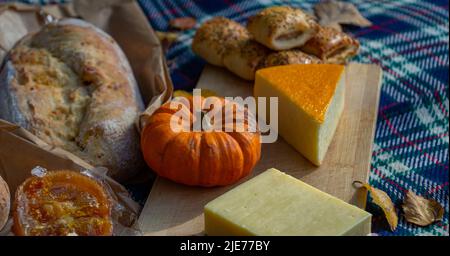 Traditionelles Herbstliches Picknick mit Sauerteig, Kürbissen und Käse auf einer rustikalen Picknick-/Platzmatte. Stockfoto