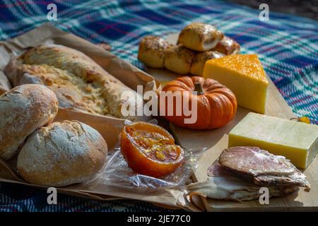 Traditionelles Herbstliches Picknick mit Sauerteig, Kürbissen und Käse auf einer rustikalen Picknick-/Platzmatte. Stockfoto