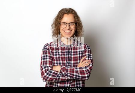 Porträt eines lächelnden jungen Mannes in einem Hemd auf weißem Hintergrund. Happy guy Student in einer Brille mit einer stilvollen Frisur. Stockfoto