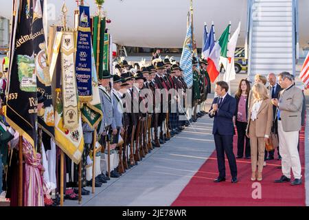 München, Deutschland. 25.. Juni 2022. Frankreichs Staatspräsident Emmanuel Macron (l.) und seine Frau Brigitte laufen am Münchner Flughafen vorbei an bayerischen Berggeflemen und Trachten, nachdem sie mit dem bayerischen Ministerpräsidenten Markus Söder (r., CSU) am Flughafen München angekommen sind. Deutschland ist Gastgeber des Gipfels der wirtschaftlich starken Demokratien G7. Am ersten Tag des Gipfels werden die globale Wirtschaftslage, der Klimaschutz sowie die Außen- und Sicherheitspolitik mit den Sanktionen gegen Russland diskutiert. Quelle: Daniel Karmann/dpa/Alamy Live News Stockfoto