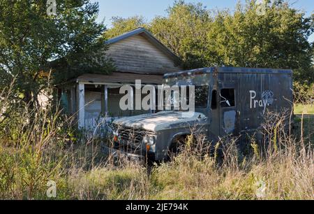 Ein alter Lastwagen steht vor einem verlassenen Haus auf einem überwucherten Grundstück in der kleinen Stadt Texola der Route 66, in der Nähe der Staatsgrenze von Texas. Stockfoto