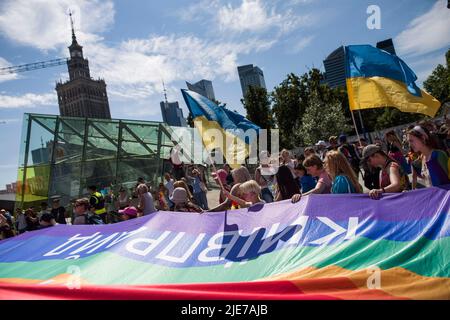 Warschau, Polen. 25.. Juni 2022. Während der Warschauer Pride halten Menschen Regenbogen- und ukrainische Fahnen fest. Die Organisation Kyiv Pride nahm an der parade zur Gleichstellung in Warschau Teil, um ihr 10.-jähriges Bestehen und die Rechte der ukrainischen LGBTQ-Bevölkerung zu feiern. Warschau und Kyiv Pride marschieren in diesem Jahr wegen der russischen Invasion in der Ukraine in der polnischen Hauptstadt zusammen. Die Warsaw Pride, auch bekannt als Equality Parade, brachte Tausende von Menschen auf die Straßen von Warschau, um die Ideen von Freiheit, Gleichheit und Toleranz zu verbreiten. Kredit: SOPA Images Limited/Alamy Live Nachrichten Stockfoto