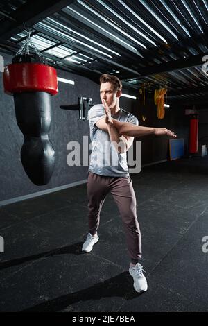 Entschlossener junger Sportler, der stehende Deltoid Stretch ausführt Stockfoto