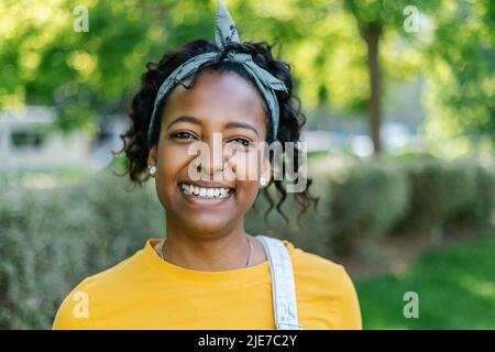 Fröhliche junge lateinamerikanische Frau, die draußen vor der Kamera lächelt Stockfoto