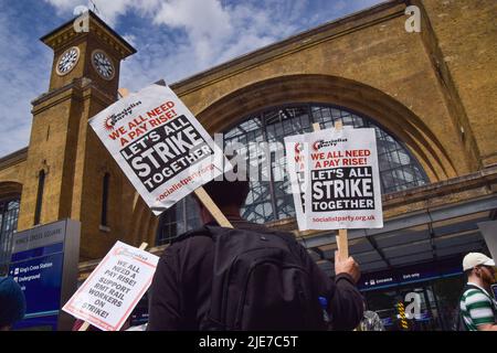 London, Großbritannien. 25.. Juni 2022. Ein Protestler hält während der Kundgebung vor der King's Cross Station Plakate mit dem Titel „Lasst uns alle zusammenschlagen“. Hunderte von Eisenbahnarbeitern und verschiedenen Gewerkschaften veranstalteten am dritten Tag des landesweiten Eisenbahnstreiks eine Kundgebung. Die Gewerkschaft RMT (Rail, Maritime and Transport Workers) veranstaltet Streikposten aus Protest gegen unbefriedigende Löhne, staatliche Kürzungen und Arbeitsbedingungen. Kredit: SOPA Images Limited/Alamy Live Nachrichten Stockfoto