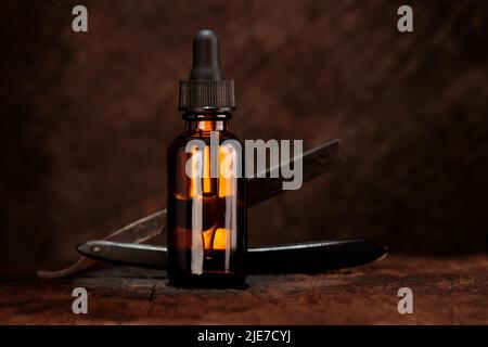 Amber Bart Ölflasche, tropper alten Rasierer und Holz im Hintergrund. Oldtimer-Bart-Öl-Mockup. Stockfoto