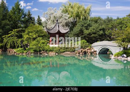 Der Pavillon der unendlichen Schönheit und eine Steinstege über den Dream Lake im Chinesischen Garten im Sommer, Montreal Botanical Garden, Quebec, Kanada. Stockfoto