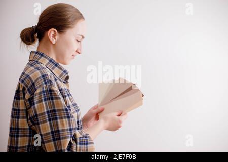 Die junge Frau hält Farbproben für die Wand in der Hand Stockfoto