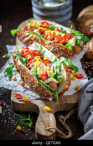 Ungesunde und leckere Hot Dogs mit Mais, Sauce und Chili. Würzige Hot Dogs aus Gemüse und Chilisauce. Stockfoto