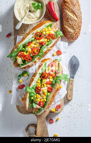 Heiße und hausgemachte Hot Dogs mit Mais, Sauce und Chili. Hausgemachte Hot Dogs mit Chilisauce und Gemüse. Stockfoto