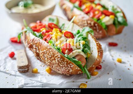 Würzige und leckere Hot Dogs mit Mais, Sauce und Chili. Hausgemachte Hot Dogs mit Chilisauce und Gemüse. Stockfoto