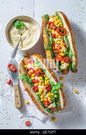 Würzige und leckere Hot Dogs mit Rucola, Chili und Mais. Hausgemachte Hot Dogs mit Chilisauce und Gemüse. Stockfoto