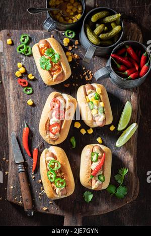 Heiße und hausgemachte Mini-Hot Dogs mit verschiedenen Belägen. Mini Hot Dogs mit bunten Zusätzen und Senf. Stockfoto