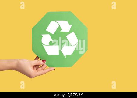 Profil Seitenansicht Nahaufnahme der Frau Hand hält Recycling-Zeichen, Ökologie, Umwelt zu sparen. Innenaufnahme des Studios isoliert auf gelbem Hintergrund. Stockfoto