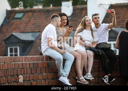 Warschau, Polen. 25.. Juni 2022. Ein Paar macht ein Selfie, während es an den alten Mauern in der Nähe des Warschauer Barbican in der Warschauer Altstadt sitzt. Tägliches Leben am Sommerabend in der Warschauer Altstadt nach einem heißen Samstag. Kredit: SOPA Images Limited/Alamy Live Nachrichten Stockfoto