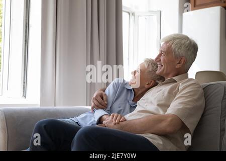 Lachendes älteres Paar in der Liebe umarmt Tagträumen entspannend auf dem Sofa Stockfoto