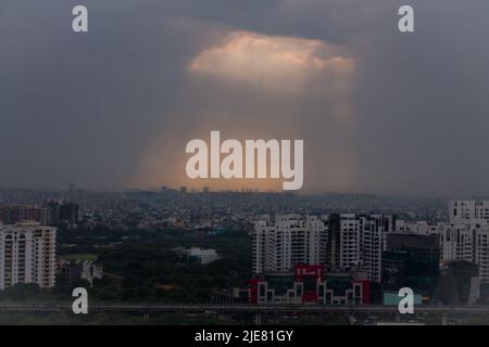 Sonnenlicht, das durch Sturmwolken strahlt und auf den Himmel von Gurugram, Haryana und Indien fällt. Delhi NCR Stadtbild bei Sonnenuntergang.Posh Business, kommerzielle Drehscheibe. Stockfoto