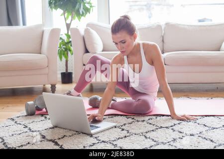 Attraktive blonde weibliche Modell tun Übung in ihrem Wohnzimmer Stockfoto