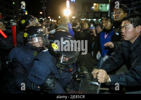 24. Nov 2003-Buan, Südkorea-die Menschen rufen mit Druck, um den Polizeischutz auf der Straße in der Innenstadt von Buan-Gun, Südkorea, anzurufen. Das Ministerium für Handel, Industrie und Energie wählt eine kleine Insel vor Buan, einem Landkreis in der Provinz Nord-Jeolla, als Standort für eine nukleare Abfallentsorgungsanlage aus. Das Projekt brach jedoch aufgrund des starken Widerstands der Einwohner von Buan im Jahr 2004 zusammen. Die Regierung beschloss im Mai 2004, Anträge von regionalen Behörden zu erhalten, die die Fazilität als Gegenleistung für finanzielle Vorteile akzeptieren möchten. Stockfoto