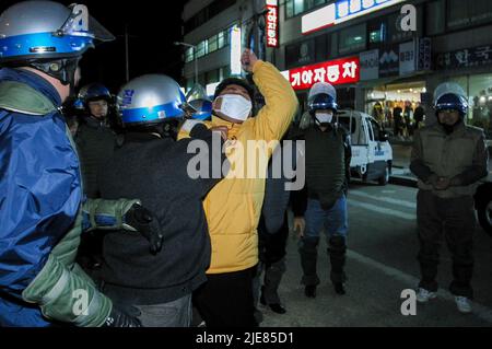 24. Nov 2003-Buan, Südkorea-Riot Polizisten verhaften einen Mann auf der Straße in der Innenstadt von Buan-Gun, Südkorea. Das Ministerium für Handel, Industrie und Energie wählt eine kleine Insel vor Buan, einem Landkreis in der Provinz Nord-Jeolla, als Standort für eine nukleare Abfallentsorgungsanlage aus. Das Projekt brach jedoch aufgrund des starken Widerstands der Einwohner von Buan im Jahr 2004 zusammen. Die Regierung beschloss im Mai 2004, Anträge von regionalen Behörden zu erhalten, die die Fazilität als Gegenleistung für finanzielle Vorteile akzeptieren möchten. Stockfoto