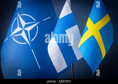 25. Juni 2022. Flaggen Finnlands und Schwedens neben dem NATO-Symbol, Konzept des Gipfels, der am 29/30. Juni in Madrid stattfinden wird und über den Zugang diskutiert Stockfoto