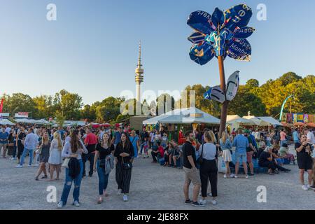 MÜNCHEN, DEUTSCHLAND - 25. JUNI 2022: Besucher kommen beim jährlichen Sommer-Tollwood-Festival im Olympiapark an Ständen vorbei. Stockfoto