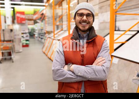 Zufriedener Käufer vor dem Hintergrund von Racks mit Finishing-Materialien Stockfoto