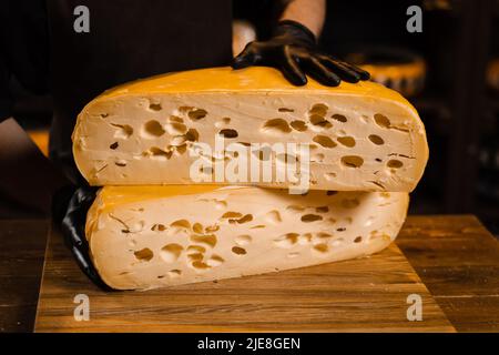 2 die Hälfte des gelben Käserads begrenzt maasdam natürlich gealtert. Käseschneiden im Laden. Große Käsestücke. Sommelier mit Käse Stockfoto