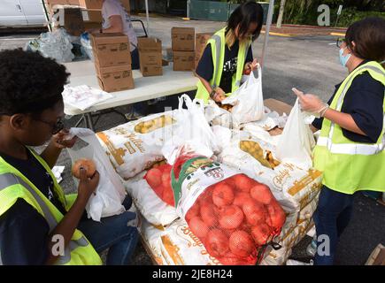 Orlando, Usa. 25.. Juni 2022. Freiwillige legen Zwiebeln und Kartoffeln in kleine Tüten bei einer Lebensmittelverteilung für Bedürftige, die von der Second Harvest Food Bank of Central Florida und Orange County in der St. John Vianney Church in Orlando, Florida, gesponsert wird. Hohe Lebensmittel- und Gaspreise drücken die arbeitenden Familien unter Druck und schicken einige zum ersten Mal in Lebensmittelvorratskammern, aber die Anbieter kämpfen mit den Inflationskosten, da die Nachfrage steigt. Kredit: SOPA Images Limited/Alamy Live Nachrichten Stockfoto